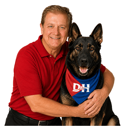 Smiling man in a red polo shirt hugging a black and tan German Shepherd wearing a blue bandana with D&H.