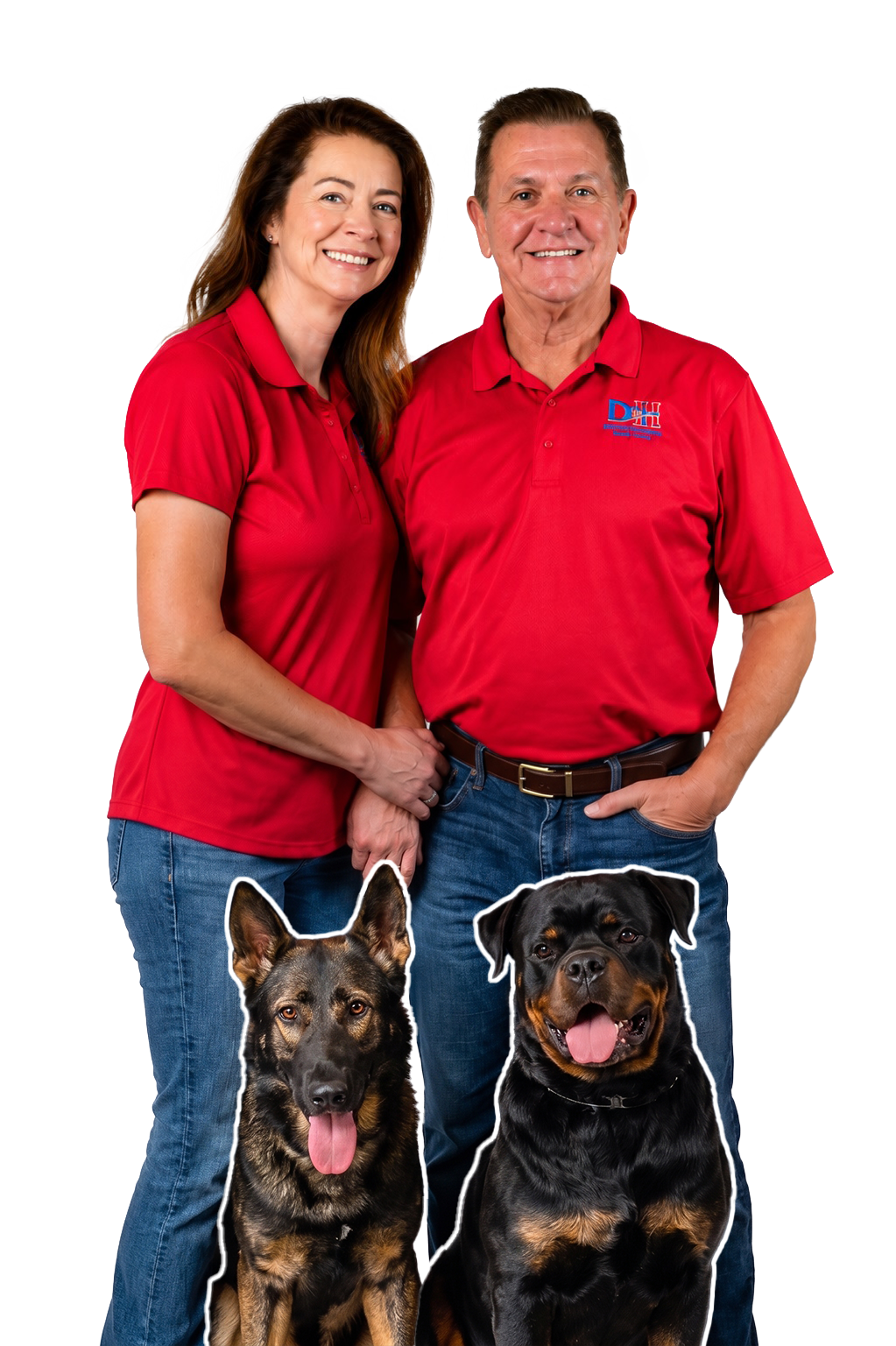 Smiling couple in red polo shirts standing behind two large dogs (German Shepherd and Rottweiler) in front.