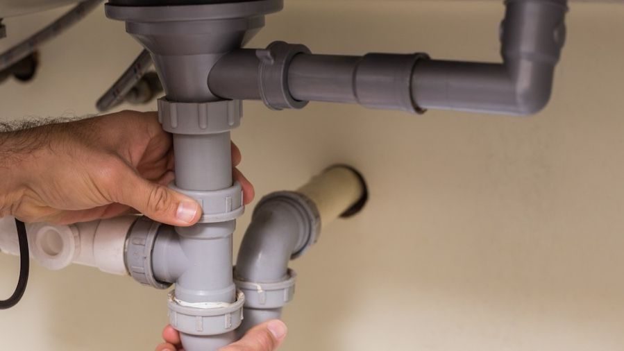 Plumber adjusting pipes after drain cleaning service.